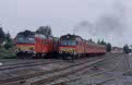 From left to right: MAV MDmot 3040 + 3 MAV coaches as passenger train from Sarand (H) to Hosszupalyi (H); MAV MDmot 3025 + 4 MAV coaches as passenger train from Nagykereki (H) to Debrecen (H) at Sarand (H) on 9 June 2002